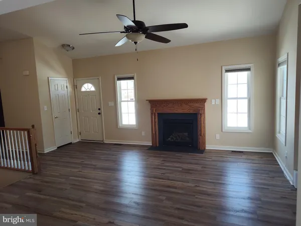 an empty room with wooden floor a ceiling fan and windows