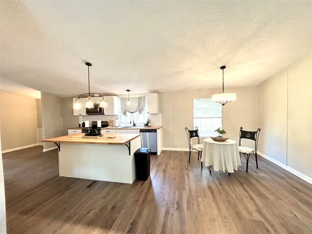 a view of a dining room and livingroom with furniture wooden floor a chandelier
