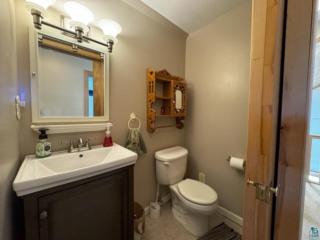 10362 Arkola Road Meadowlands, MN 55765 - Photo 16 of 30 Bathroom with toilet, vanity, baseboards, and tile patterned flooring