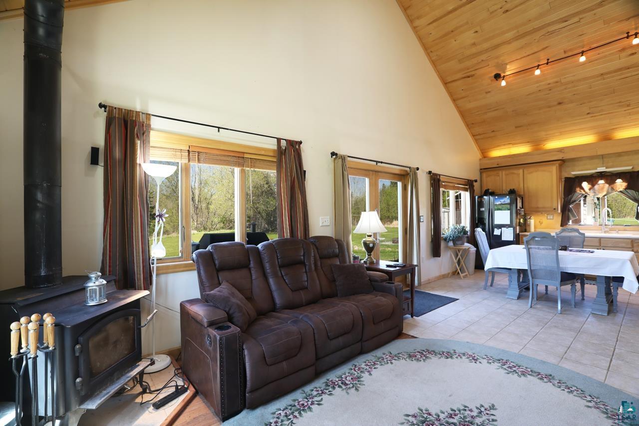10362 Arkola Road Meadowlands, MN 55765 - Photo 3 of 30 Living room with a wood stove, high vaulted ceiling, wooden ceiling, rail lighting, and light tile patterned floors