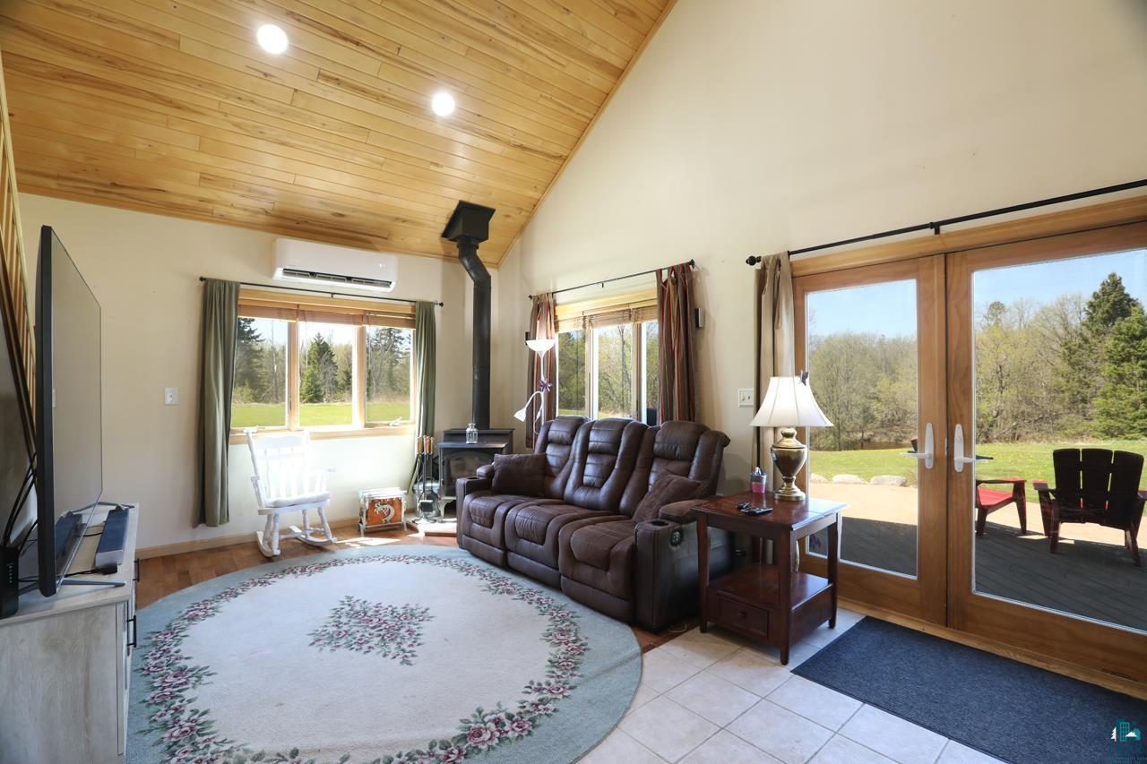 10362 Arkola Road Meadowlands, MN 55765 - Photo 4 of 30 Living room featuring a wood stove, french doors, a wall unit AC, wooden ceiling, and recessed lighting