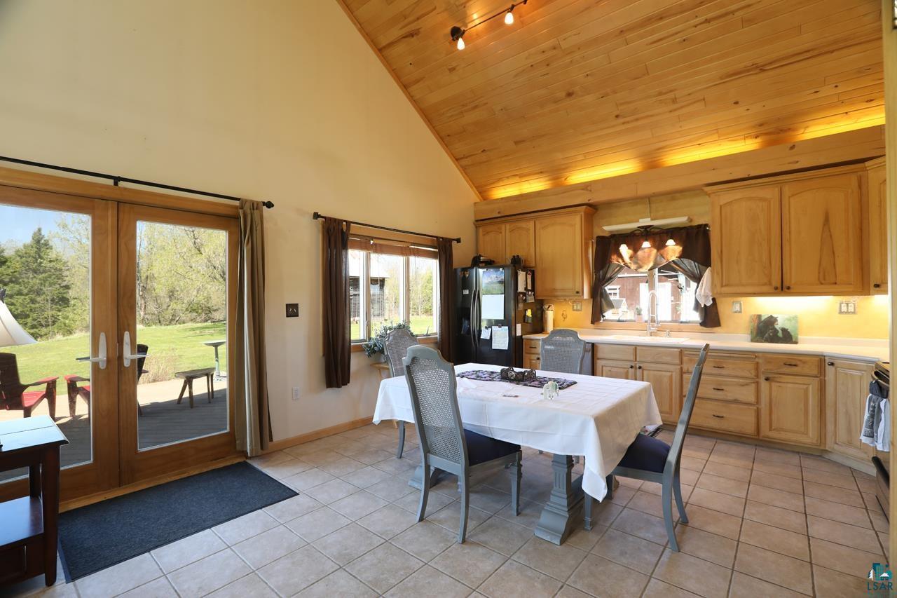 10362 Arkola Road Meadowlands, MN 55765 - Photo 6 of 30 Dining area featuring wooden ceiling, light tile patterned floors, french doors, healthy amount of natural light, and high vaulted ceiling