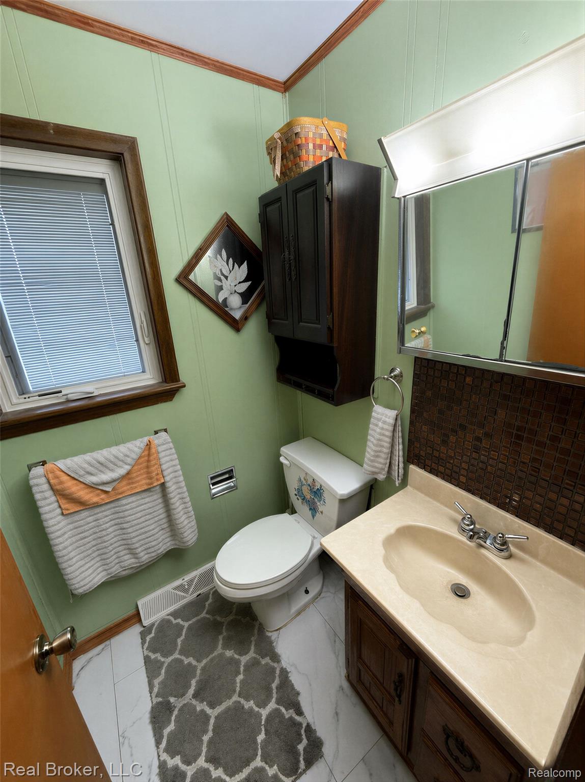 3412 South Reese Road Frankenmuth, MI 48734 - Photo 9 of 17 Half bath with vanity, a decorative wall, and ornamental molding