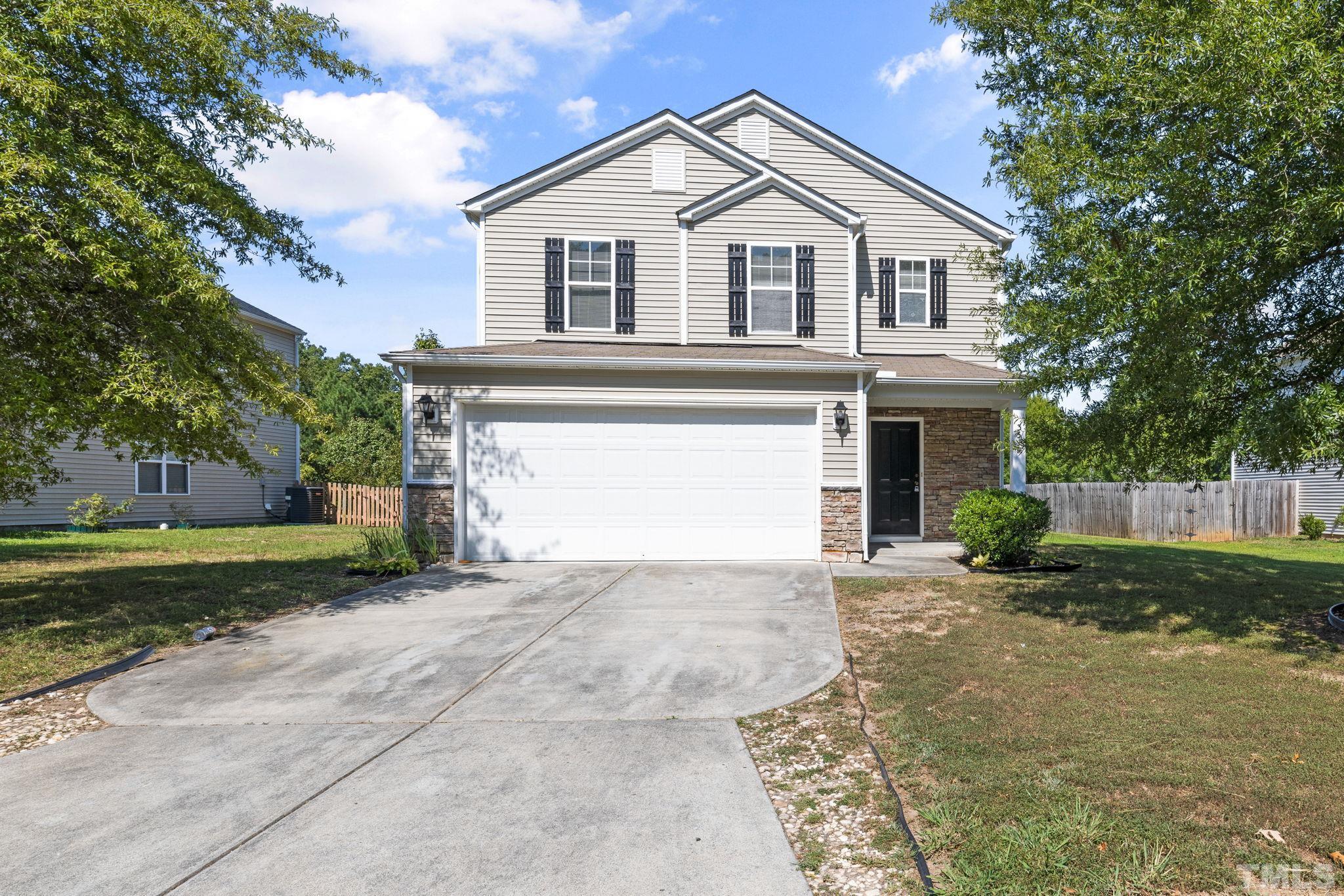 a view of a house with a yard and large tree