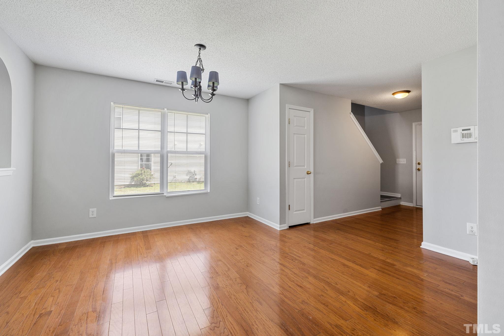 3519 Mountain Brook Circle Durham, NC 27704 - Photo 8 of 24 an empty room with wooden floor chandelier and windows