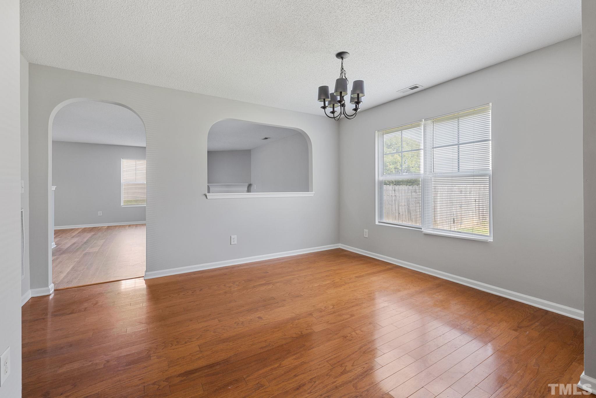 3519 Mountain Brook Circle Durham, NC 27704 - Photo 9 of 24 an empty room with wooden floor chandelier and windows