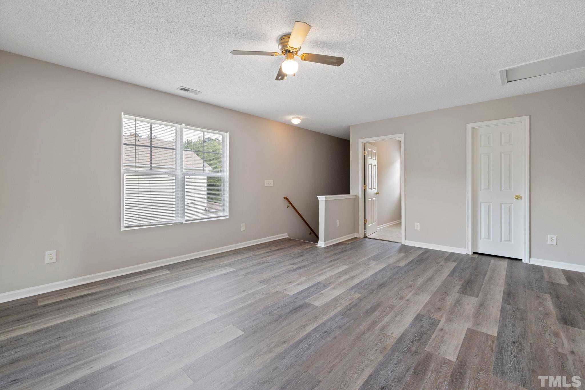 3519 Mountain Brook Circle Durham, NC 27704 - Photo 10 of 24 an empty room with wooden floor chandelier fan and windows