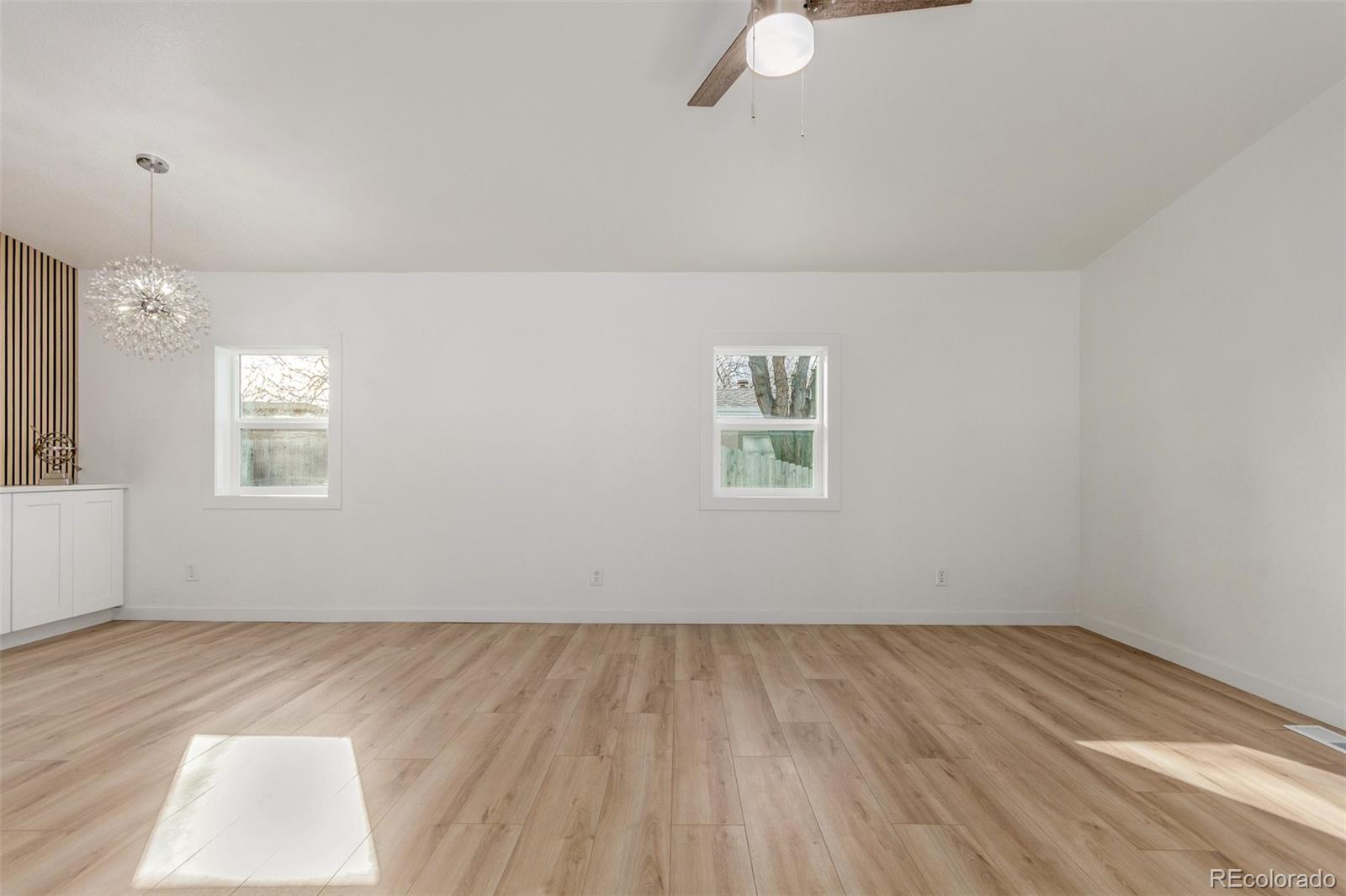 8466 Adams Way Denver, CO 80229 - Photo 11 of 31 an empty room with wooden floor fan and windows