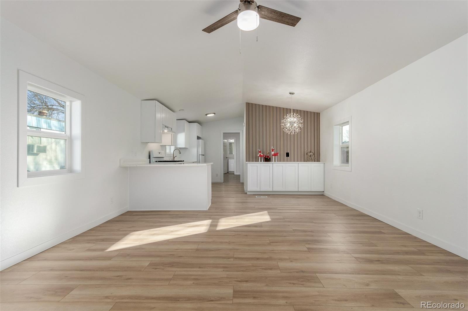 8466 Adams Way Denver, CO 80229 - Photo 12 of 31 a view of an empty room with wooden floor and a kitchen