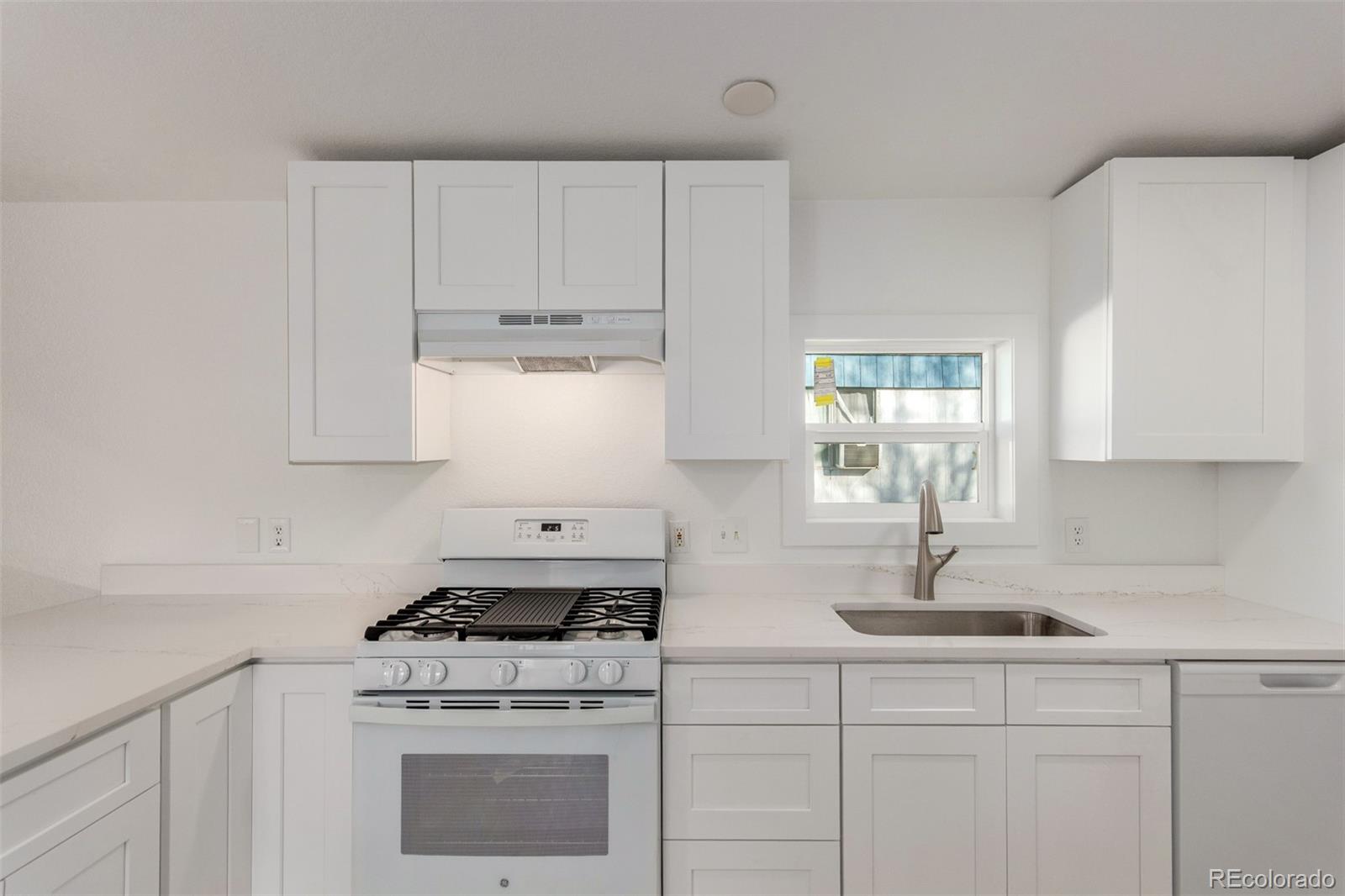 8466 Adams Way Denver, CO 80229 - Photo 18 of 31 a kitchen with white cabinets and white appliances