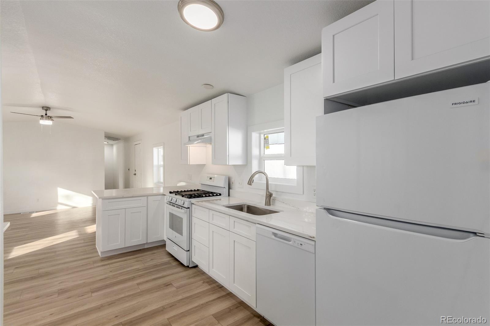 8466 Adams Way Denver, CO 80229 - Photo 19 of 31 a kitchen with a sink a stove a refrigerator and white cabinets