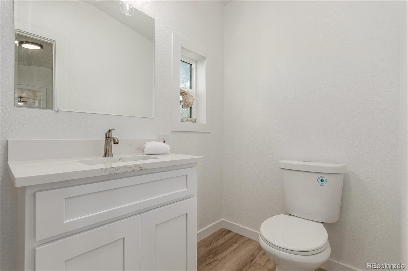 8466 Adams Way Denver, CO 80229 - Photo 23 of 31 a bathroom with a toilet a sink and mirror