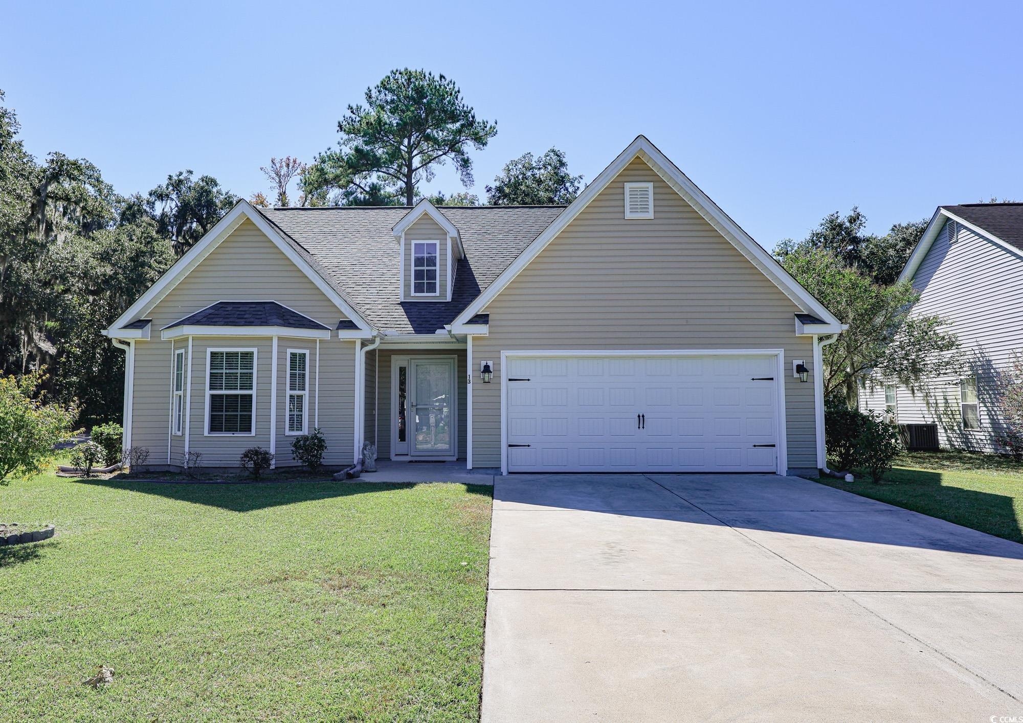 View of front facade featuring a front lawn, roof with shingles, concrete driveway, and an attached garage