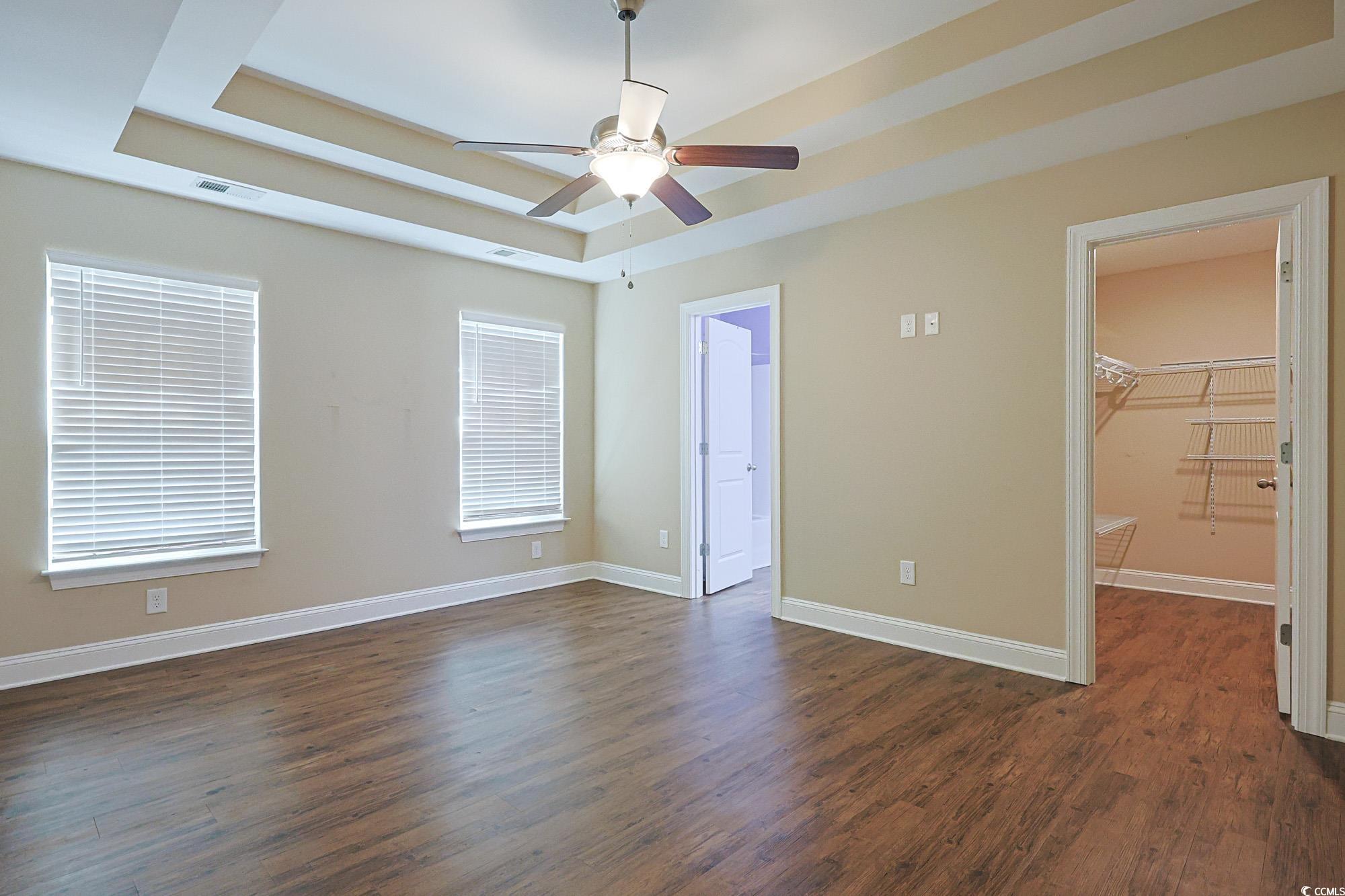 13 Daniel Morrall Lane Georgetown, SC 29440 - Photo 11 of 30 Unfurnished bedroom with a tray ceiling, dark wood finished floors, a spacious closet, and ceiling fan