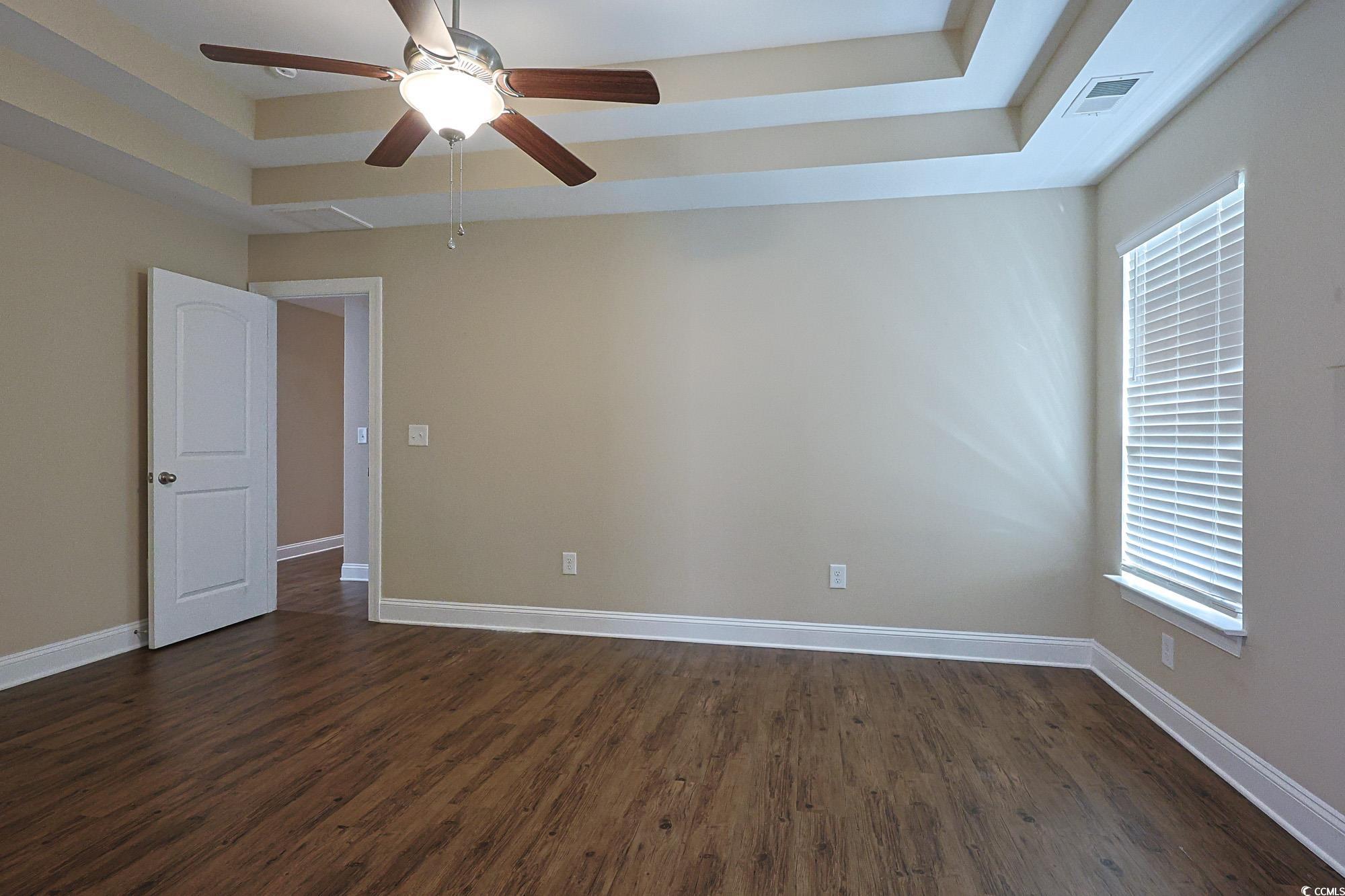 13 Daniel Morrall Lane Georgetown, SC 29440 - Photo 13 of 30 Spare room with a tray ceiling, dark wood-type flooring, and ceiling fan
