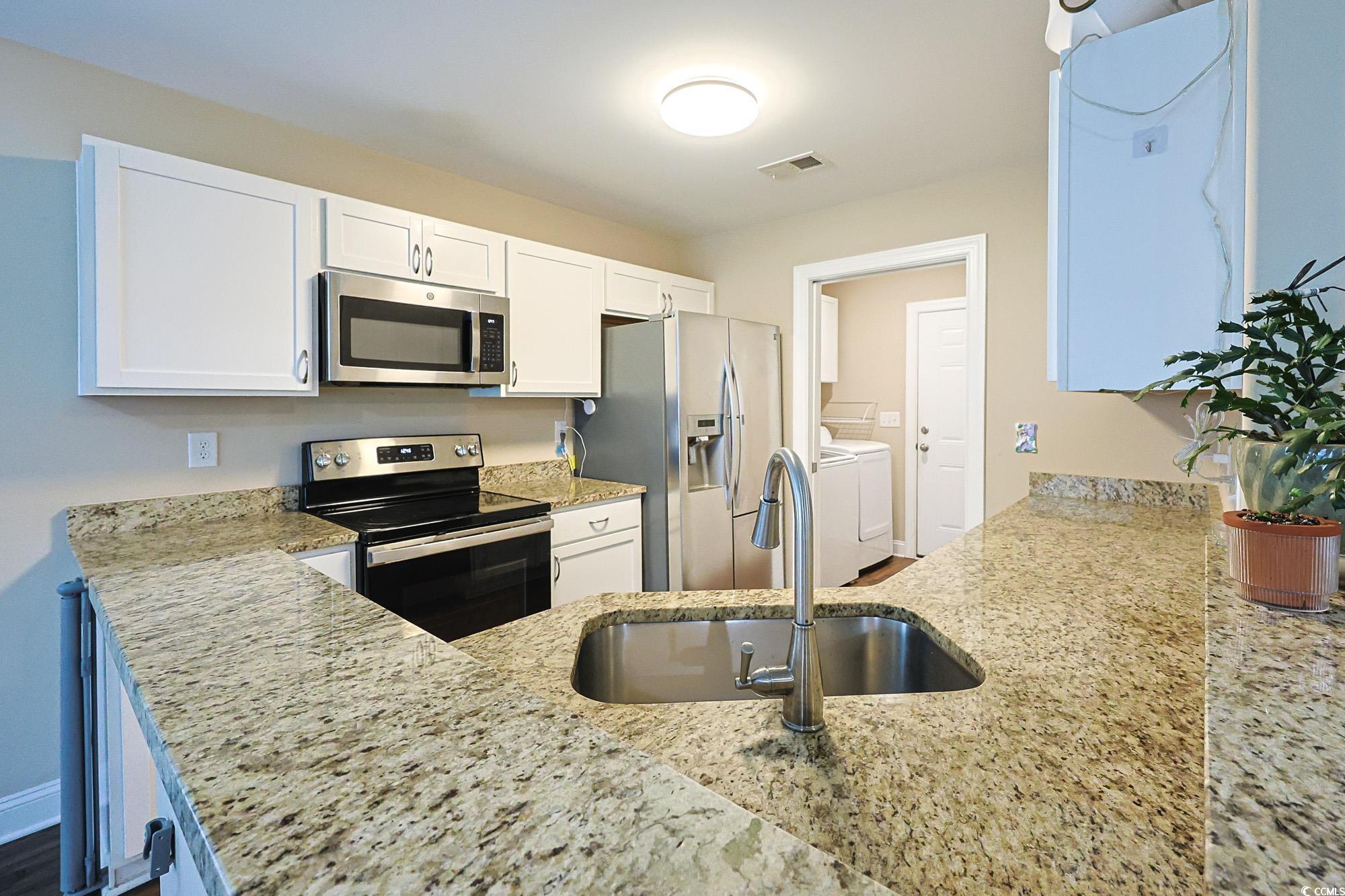 13 Daniel Morrall Lane Georgetown, SC 29440 - Photo 7 of 30 Kitchen featuring appliances with stainless steel finishes, white cabinets, light stone countertops, and a peninsula