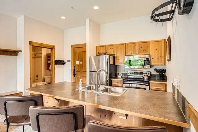 a kitchen with stainless steel appliances granite countertop a stove a refrigerator a dining table and chairs with wooden floor