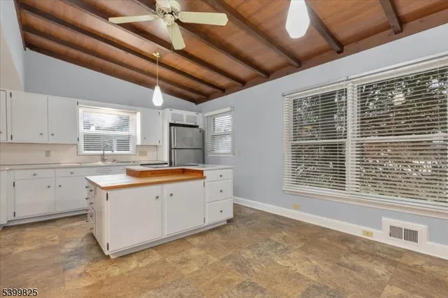 a large white kitchen with granite countertop a sink window and cabinets