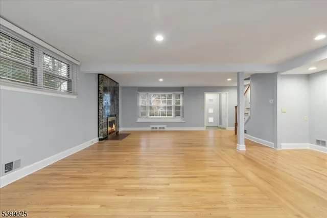 a view of an empty room with window and wooden floor
