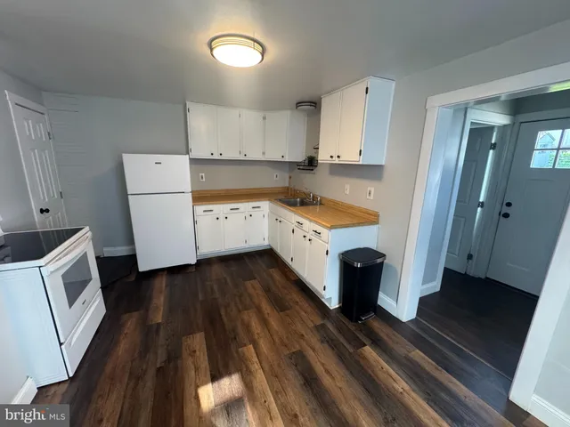 a kitchen with a refrigerator wooden floor and white cabinets
