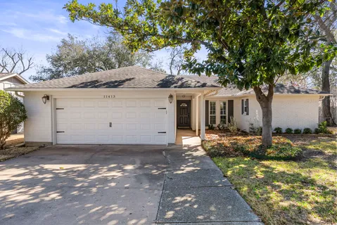 a view of a white house next to a yard and a large tree