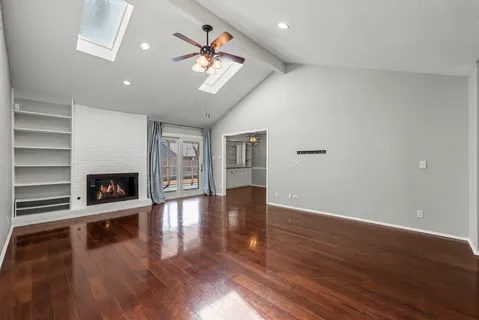 a view of an empty room with wooden floor and a fireplace