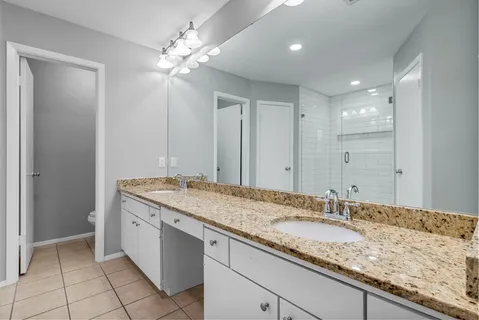 a bathroom with a granite countertop sink a large mirror and a shower