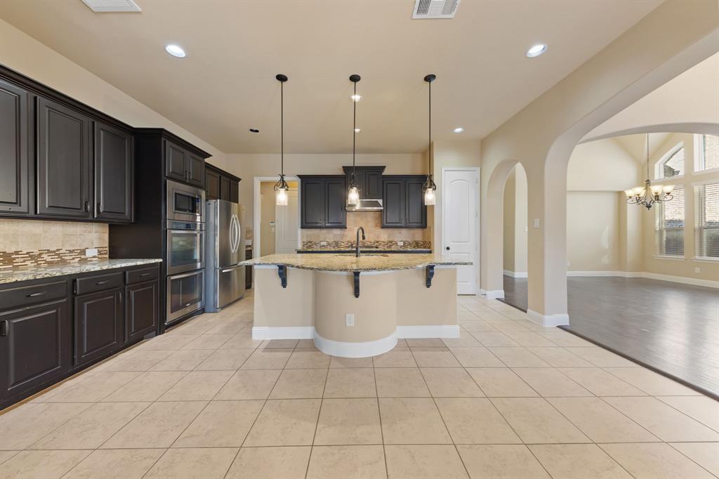 8336 Pitkin Road Frisco, TX 75036 - Photo 15 of 40 a large kitchen with kitchen island a counter a sink a counter and cabinets