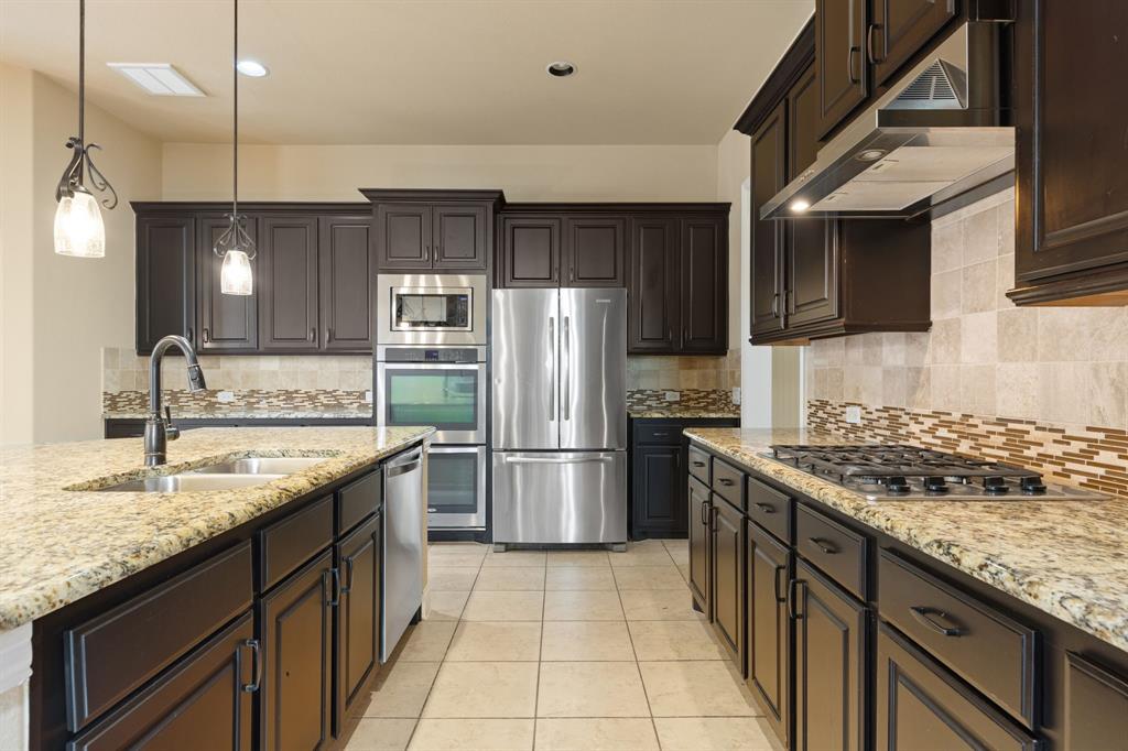 8336 Pitkin Road Frisco, TX 75036 - Photo 17 of 40 a kitchen with stainless steel appliances granite countertop a sink stove and refrigerator