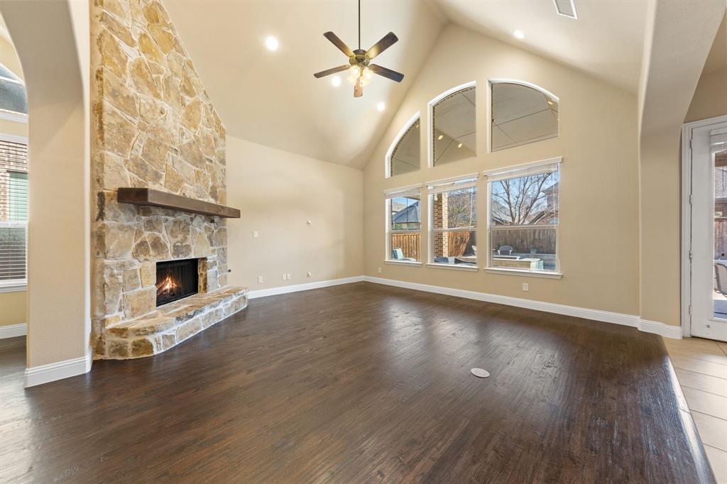 8336 Pitkin Road Frisco, TX 75036 - Photo 10 of 40 an empty room with wooden floor a ceiling fan and a fireplace