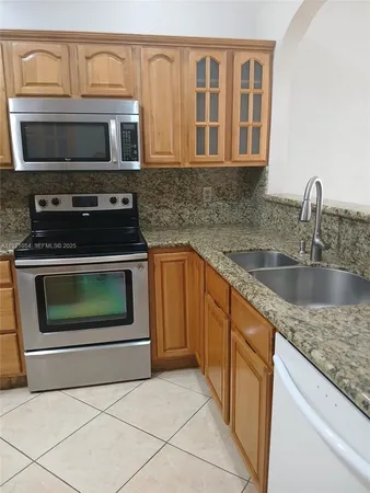 a kitchen with granite countertop a stove top oven microwave and cabinets