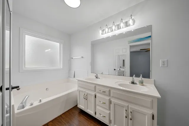 a bathroom with a double vanity sink mirror and bathtub