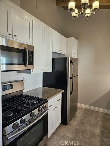 a kitchen with stainless steel appliances granite countertop a refrigerator stove and white cabinets