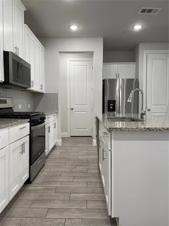 a kitchen with stainless steel appliances granite countertop a refrigerator and a stove top oven