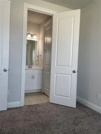 an empty room with mirror and a bathroom
