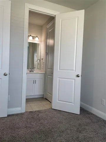 an empty room with mirror and a bathroom
