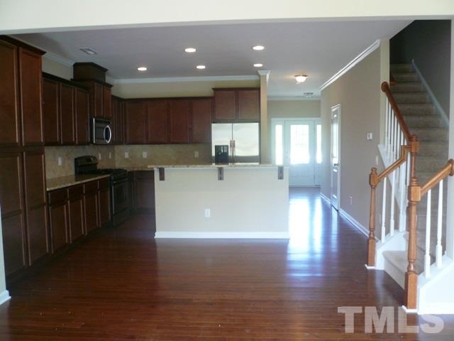 213 Irving Way, Unit 69 Durham, NC 27703 - Photo 3 of 25 a view of a kitchen with kitchen island a sink wooden floor and a counter top space