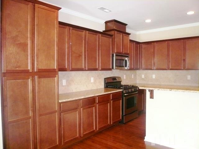 213 Irving Way, Unit 69 Durham, NC 27703 - Photo 4 of 25 a kitchen with stainless steel appliances granite countertop a refrigerator a sink dishwasher and wooden cabinets with wooden floor