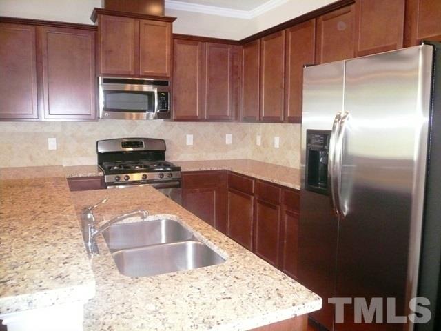 213 Irving Way, Unit 69 Durham, NC 27703 - Photo 6 of 25 a kitchen with stainless steel appliances granite countertop a refrigerator a stove and a sink with wooden cabinets