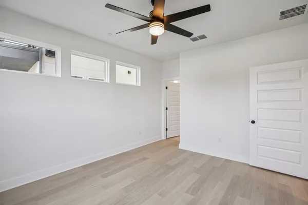 an empty room with a ceiling fan and wooden floor
