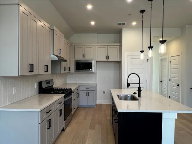 a kitchen with stainless steel appliances a sink a stove a refrigerator and cabinets