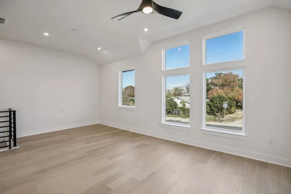 an empty room with windows and ceiling fan