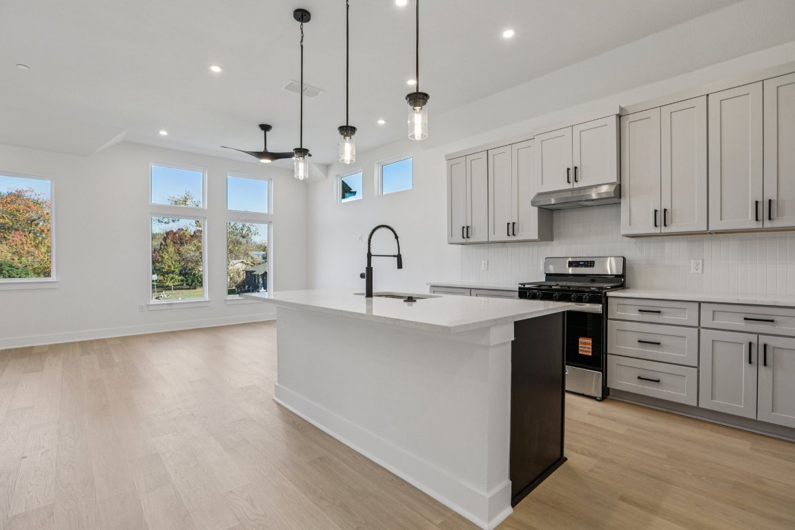 200 West 56th Street, Unit 2104 Austin, TX 78751 - Photo 7 of 36 a kitchen with stainless steel appliances granite countertop a sink a stove a refrigerator and white cabinets with wooden floor