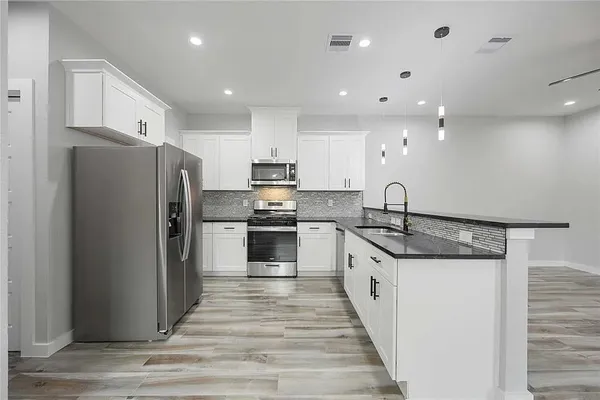 a kitchen with stainless steel appliances granite countertop a refrigerator and a stove
