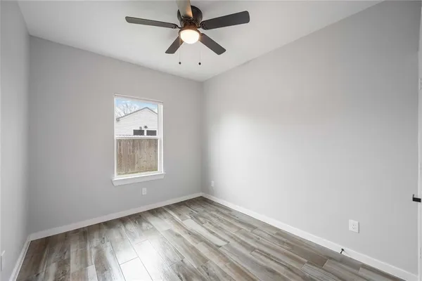 an empty room with wooden floor chandelier fan and windows