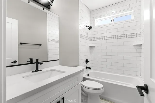 a bathroom with a sink a toilet a mirror a bathtub and shower