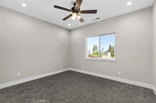 an empty room with window and ceiling fan