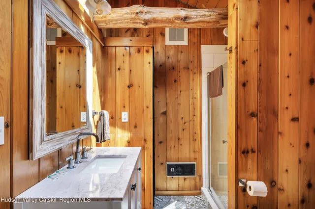 a bathroom with a granite countertop double vanity sink a mirror and a shower