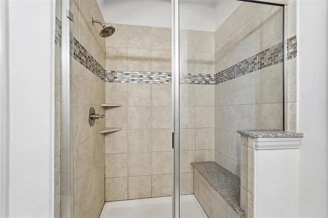 a bathroom with a granite countertop sink two mirror and shower