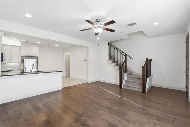 a view of an empty room with wooden floor and a ceiling fan